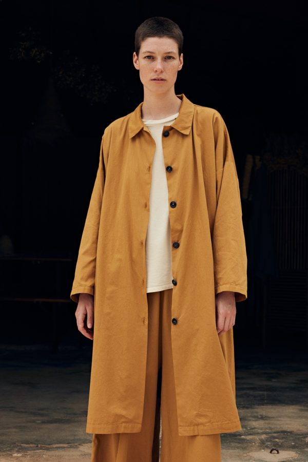 front view of the model wearing the cape duster opened up and wrap pants in amber color