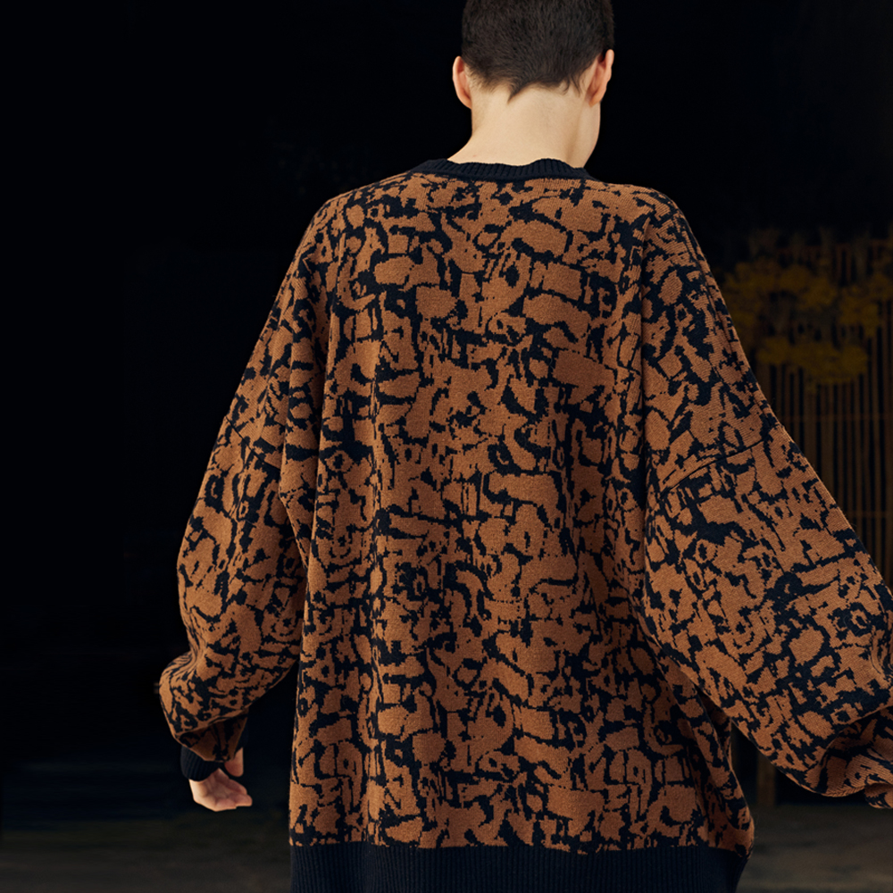 back view of the model wearing the artist sweater in black and earth color